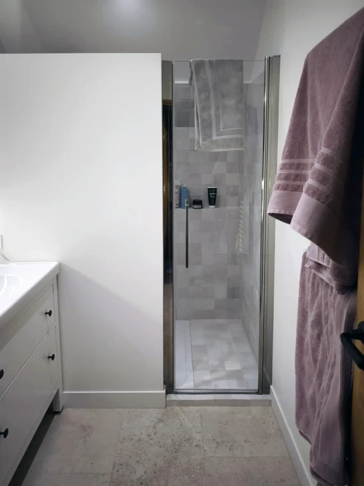 Salle de bain moderne avec douche à l'italienne équipée d'une paroi vitrée pivotante et robinetterie thermostatique