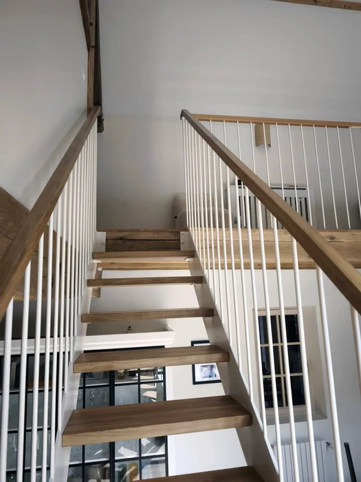 Escalier intérieur en bois avec structure ouverte et garde-corps à barreaux blancs verticaux