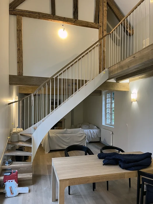 Intérieur d'un logement rénové avec mezzanine, escalier droit à rampe métallique blanche et barreaux verticaux