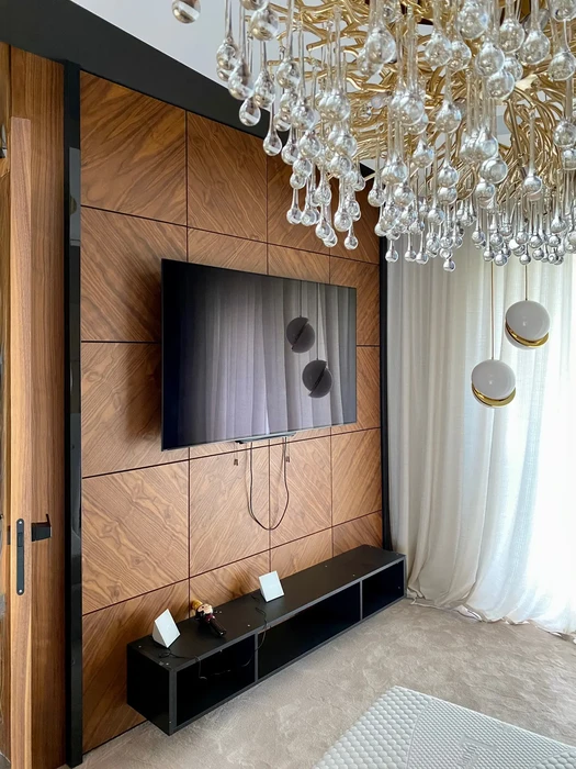 Salon moderne avec meuble TV mural en bois à motifs géométriques, écran plat intégré, console noire au sol