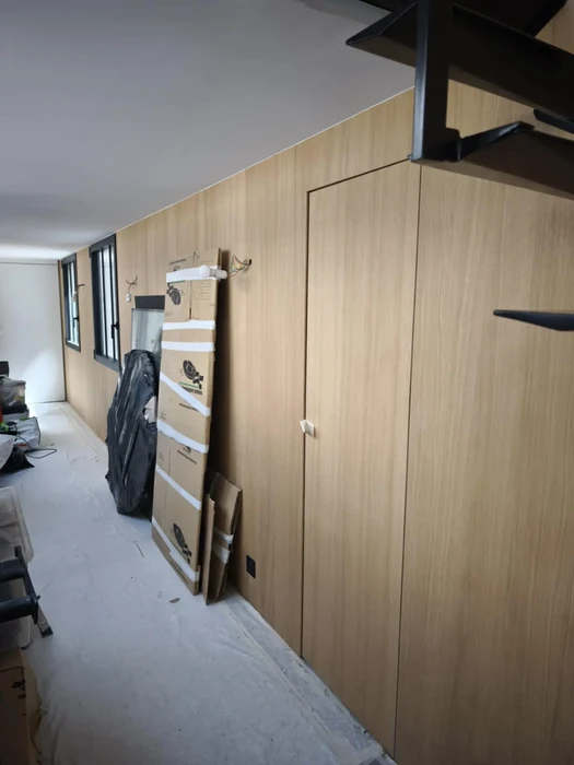Intérieur moderne sous combles avec poutres apparentes en bois ancien, murs blancs et parquet clair
