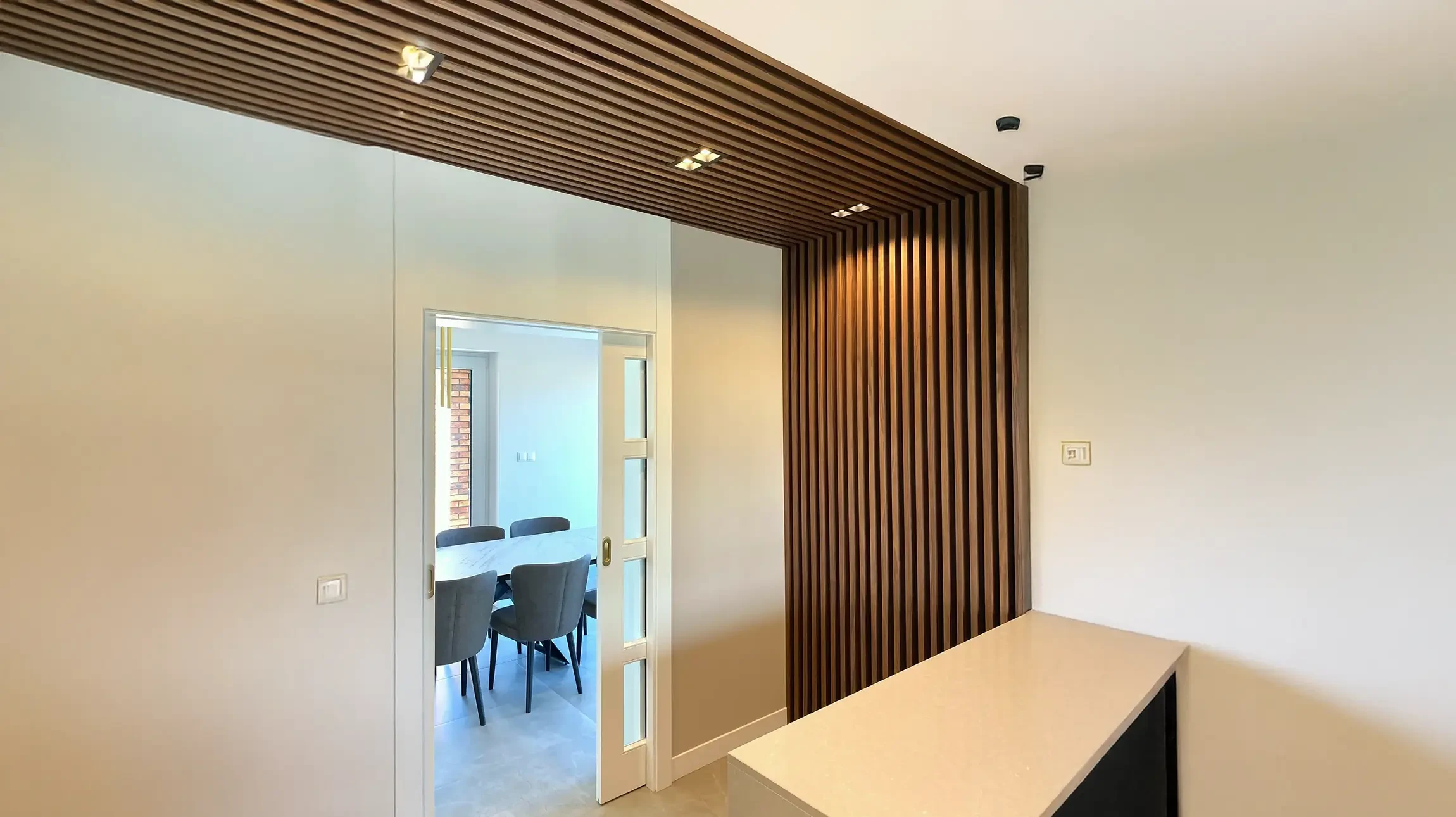 Intérieur moderne avec cloison décorative en lamelles de bois verticales créant une séparation entre espaces