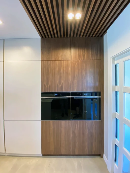 Intérieur de cuisine moderne en cours d'aménagement avec îlot central blanc à tiroirs, mezzanine avec escalier et garde-corps métallique