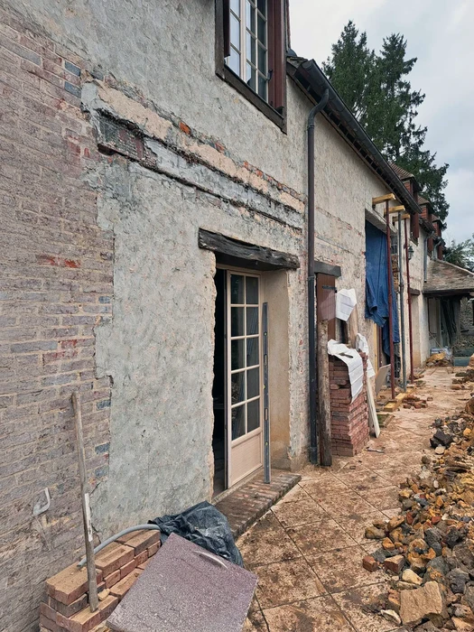 Salle de bain moderne compacte avec douche à l'italienne vitrée, meuble vasque suspendu en bois naturel, plan de toilette blanc, vasque à poser ronde blanche, robinetterie murale chromée, miroir ovale sans cadre, carrelage mural beige effet béton ciré, éclairage LED intégré au plafond, interrupteur mural blanc